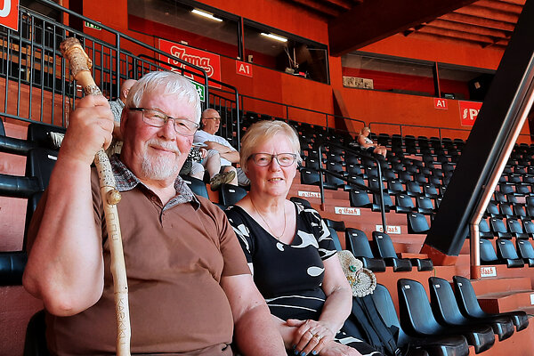 Mies ja nainen istuvat pesäpallostadionin katsomossa