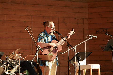Katso suurempi versio kuvasta Jaakko Löytty soittaa kitaraa ja huuliharppua Ilosaaren esiintymislavalla.