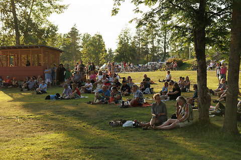Katso suurempi versio kuvasta Ihmisiä istumassa nurmikolla Ilosaaressa.