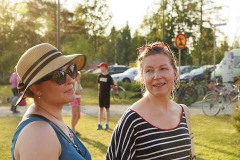 Katso suurempi versio kuvasta Kaksi naista lähikuvassa, taustalla nuoria ja autoja.
