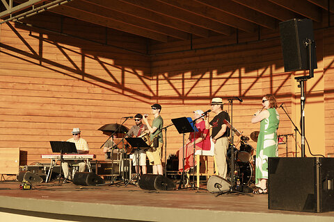 Katso suurempi versio kuvasta Yhtye esiintymässä Ilosaaren esiintymislavalla. Kuvassa kosketinsoittaja, kitaristi, perkussioiden soittaja, kaksi laulajaa ja huilisti.